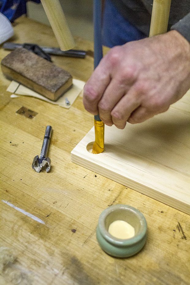 Un pinceau est utilisé pour ajouter colle à bois sur les trous et les chevilles pour connecter l'unité de rayonnage ensemble.