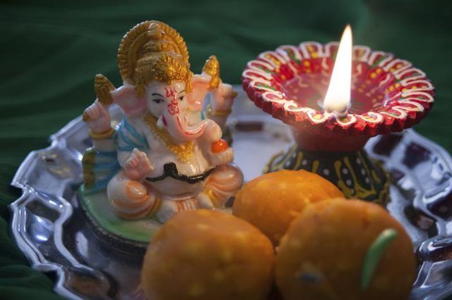 Une statue de Ganesh, prière bougie et friandises sur une plaque.