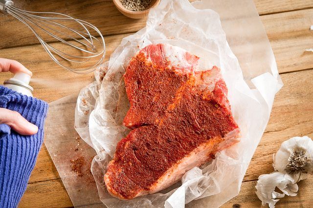 Raw T-bone steak pulvérisé avec l'huile de cuisson.