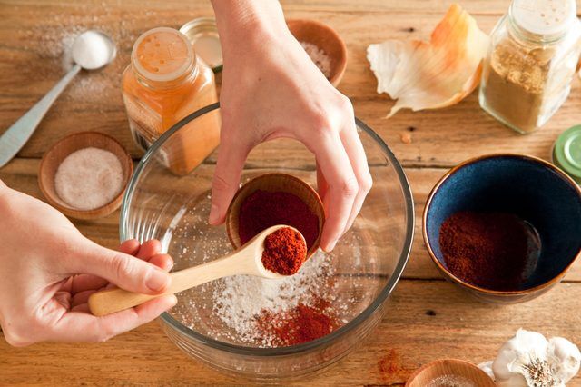 Paprika dans une cuillère à mesurer ajouté à un bol de verre des ingrédients.